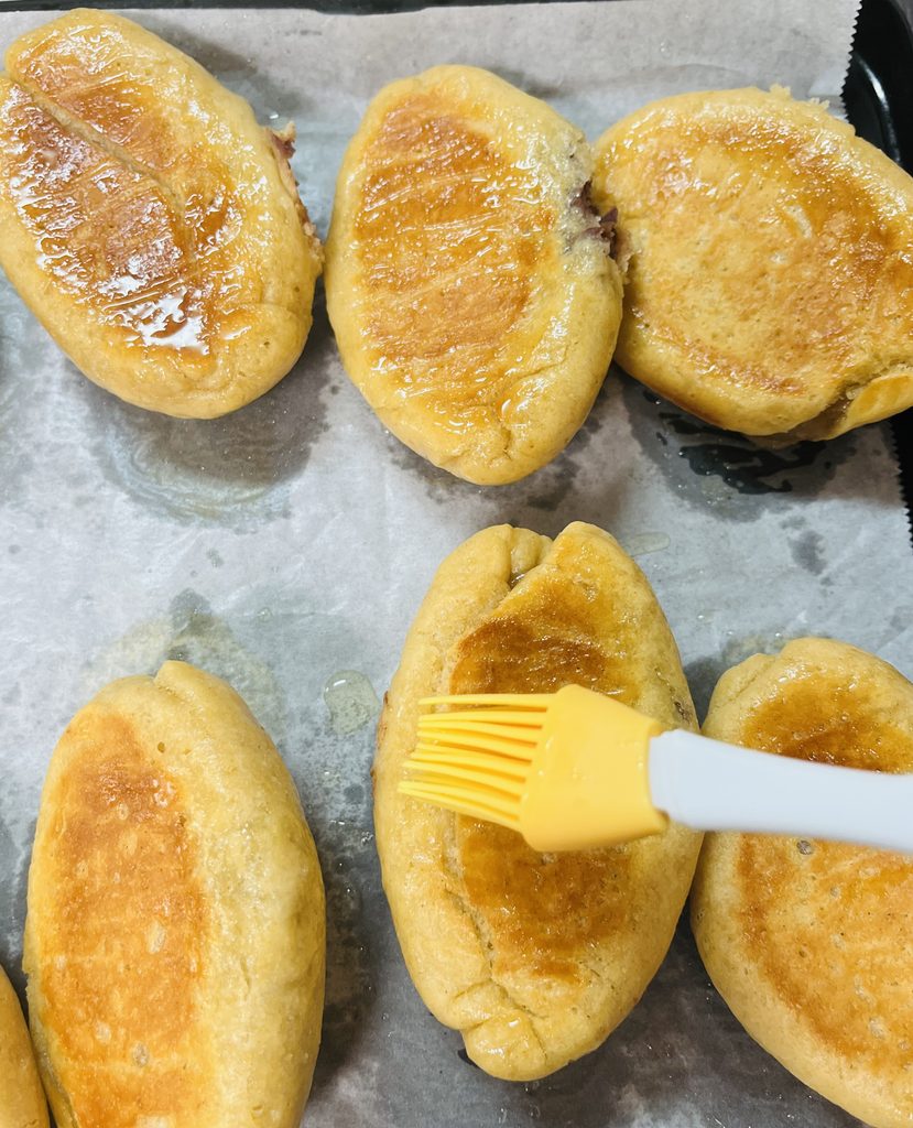 焼き上がったパンに、熱いうちに刷毛で米油を塗っているところ