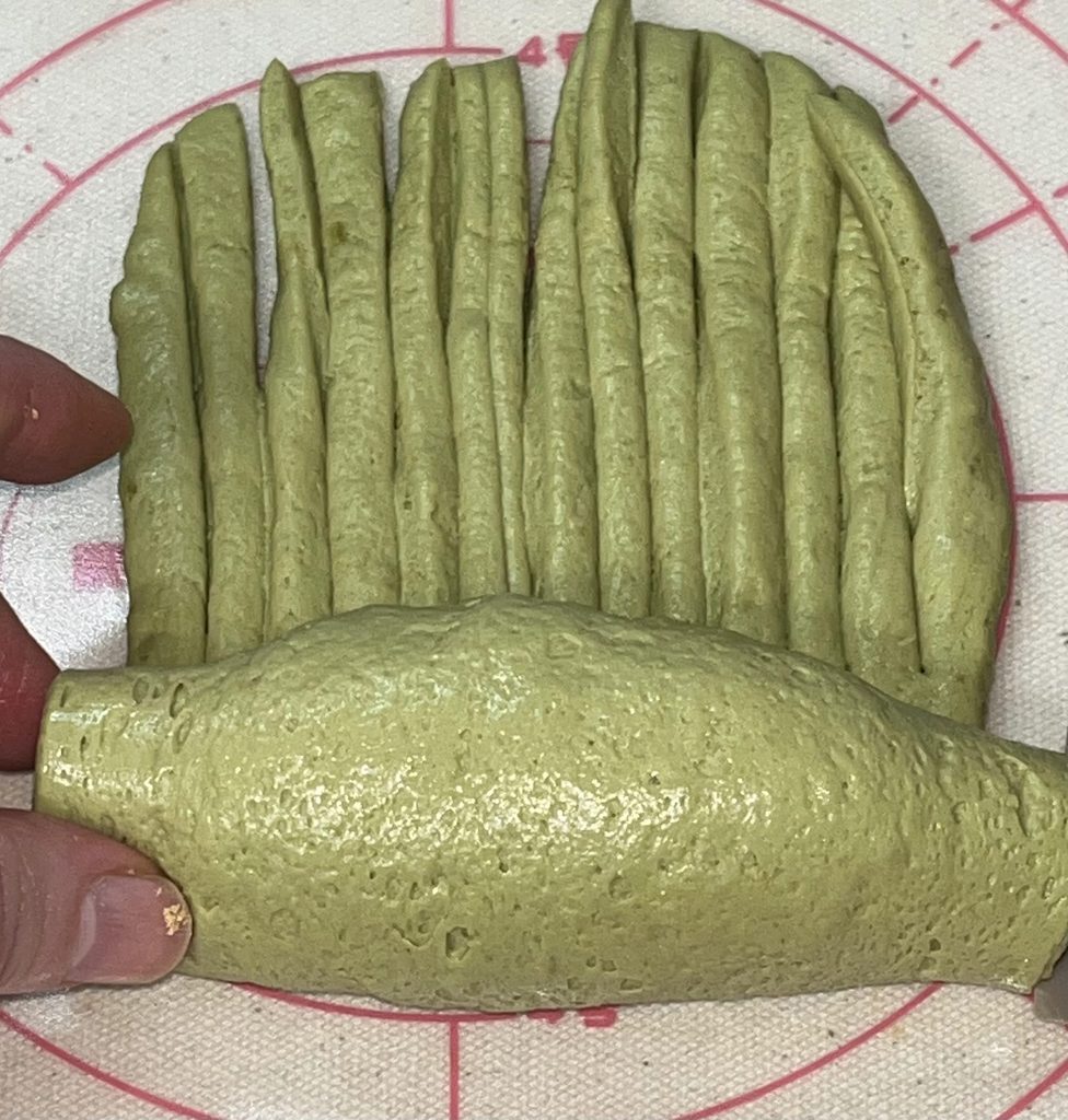 切り込みを入れた抹茶の生地を巻いているところ