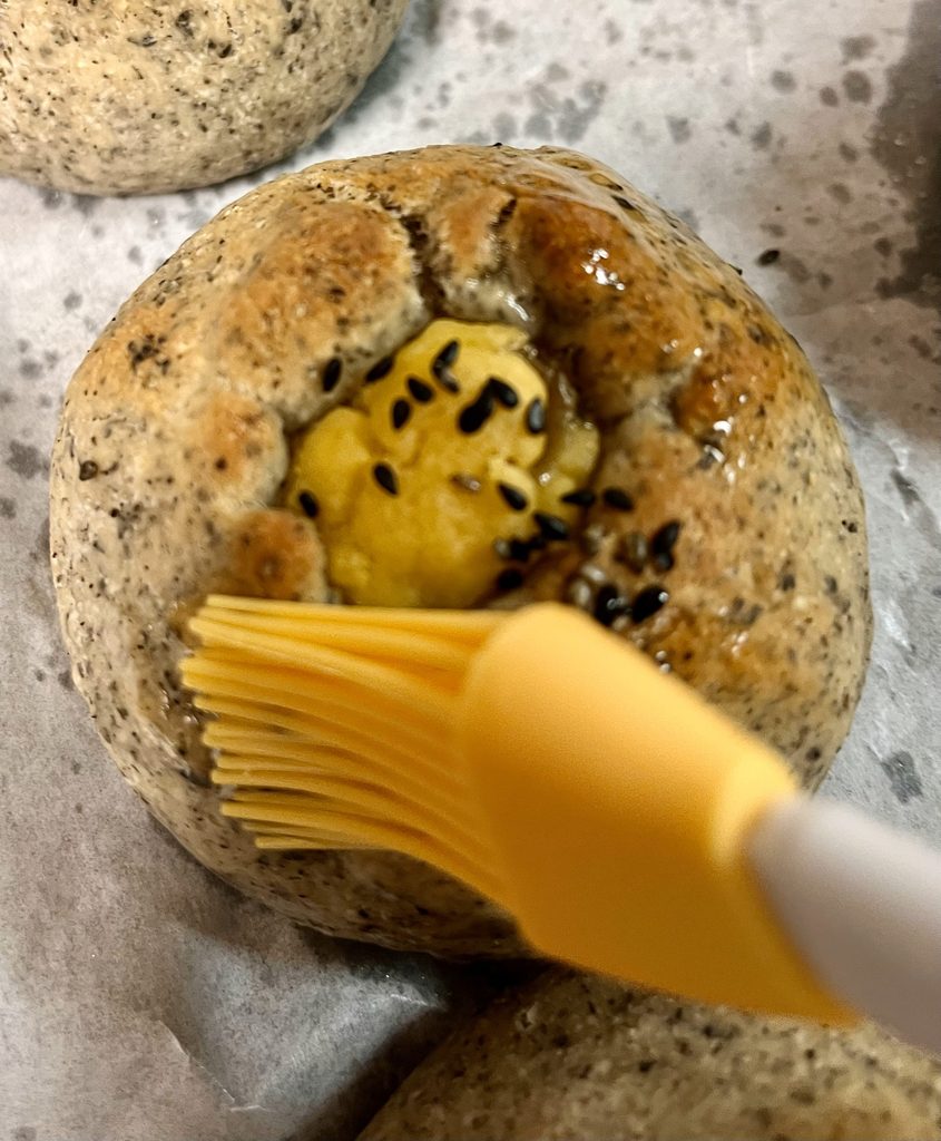 焼き上がった巾着パンに、熱いうちに刷毛で米油を塗っているところ