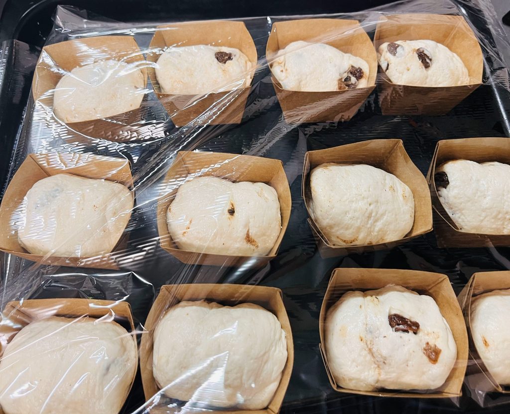 発酵させるためにラップをかけた、紙のキューブ型に入った生地