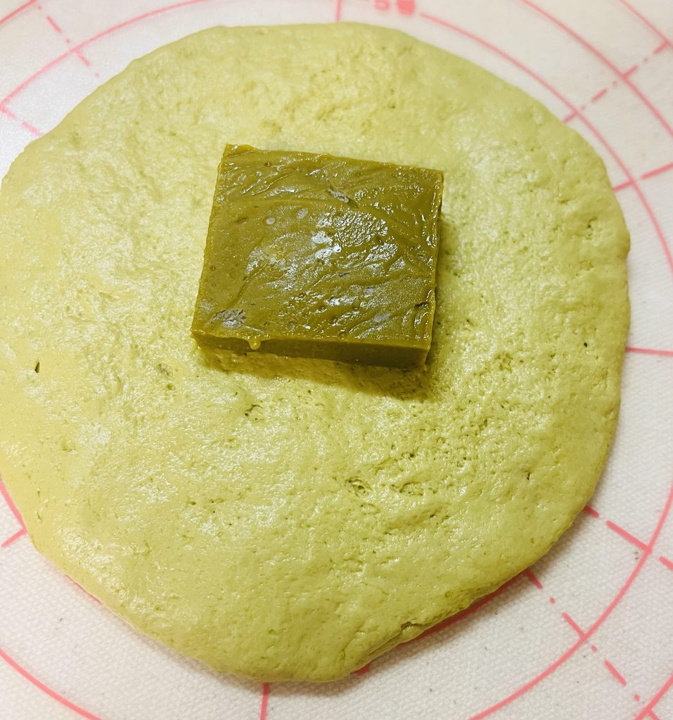 丸く広げた抹茶の生地に、凍らせたカスタードを1切れのせたところ