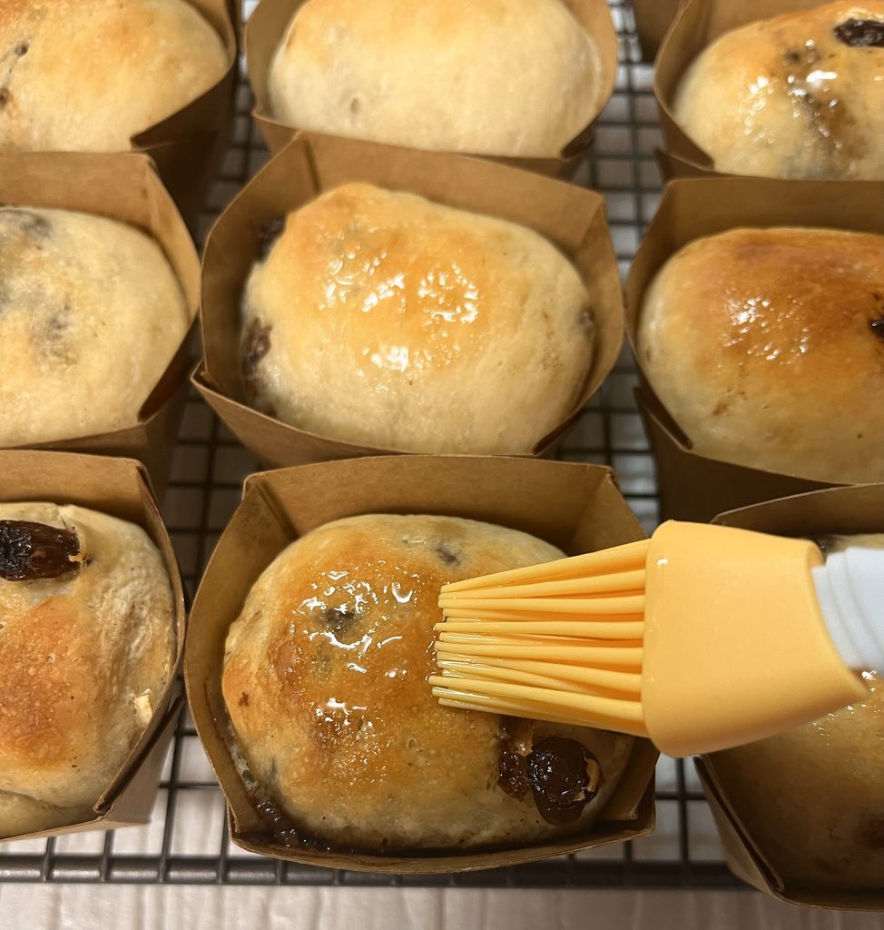 焼き上がった米粉のりんごパンに、熱いうちに刷毛で米油を塗っているところ